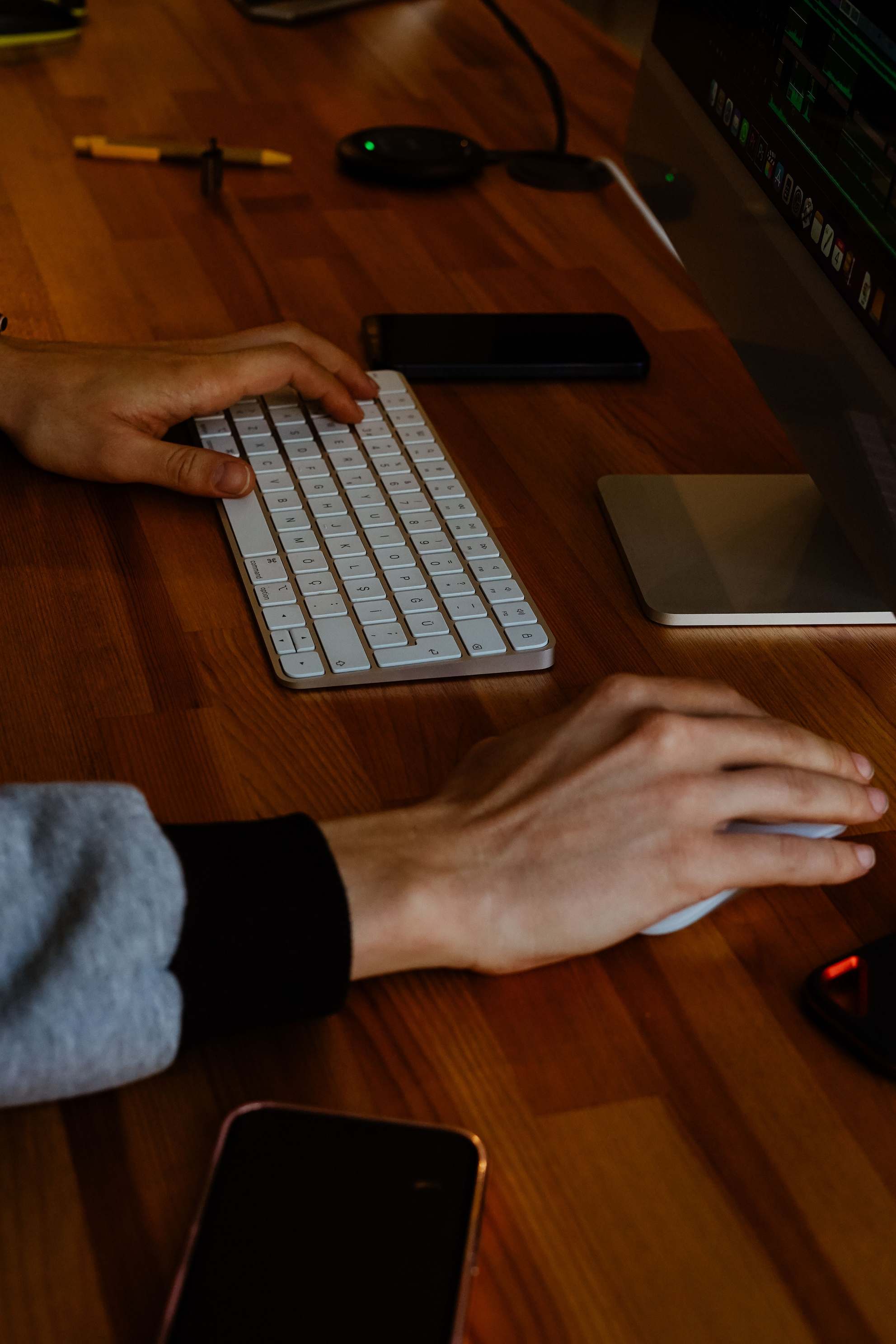 Hände an Tastatur und Maus vor Monitor mit Tabellendaten